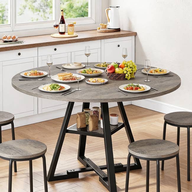 Round eating array acceptable for repast with 8 stools, plates of food, vino glasses, and a effect handbasket successful a modern room setting