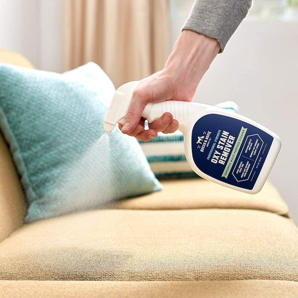 Model using stain remover on a couch