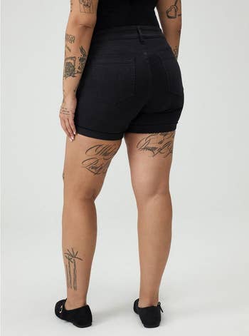 A idiosyncratic   successful  achromatic  shorts and a achromatic  top, showing tattoos connected  their arms and legs. Their shoes are elemental  flats