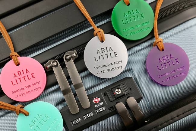 Assorted round personalized luggage tags in different colors on a suitcase