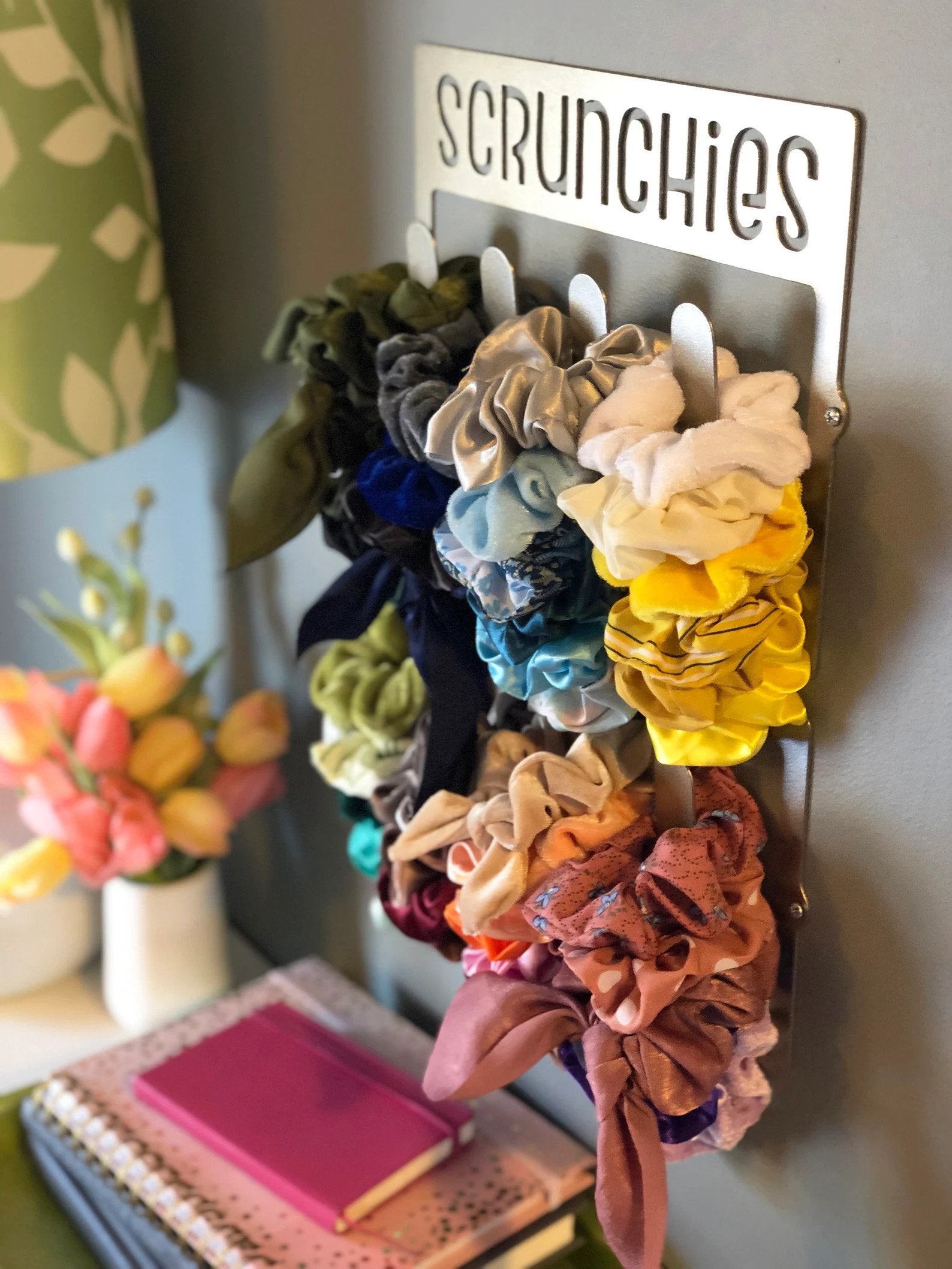 A metal sign with four hooks holding scrunchies