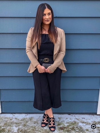 reviewer wearing the black belt with a black jumpsuit and tan blazer