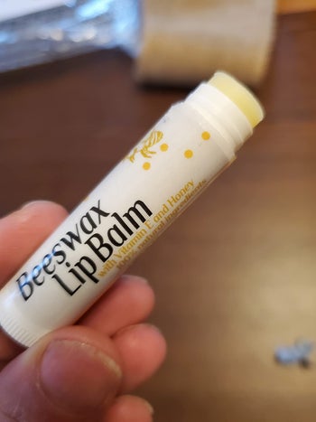 a reviewer showing the tube of lip balm without the cap