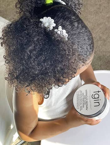 Child model with healthy-looking curls and holding the product