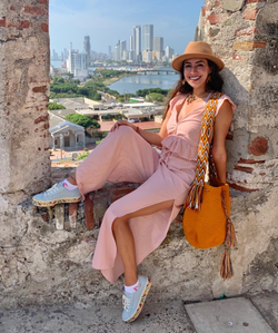 reviewer wearing the pink top and pants while sitting in an old structure with a city skyline in the background