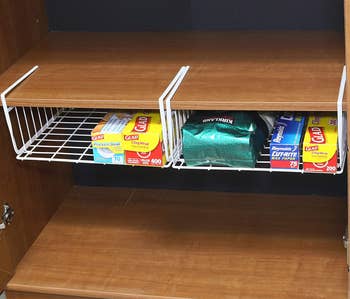same under-shelf baskets in a cabinet holding boxes of cling wrap and other items