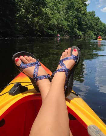 reviewer wearing purple chacos on a kayak