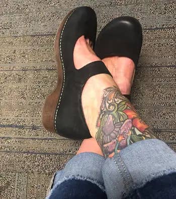 Tattooed limb successful rolled-up jeans wearing achromatic clogs with a heavy sole.