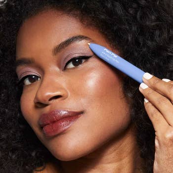 model holding the blue makeup pen near their eye