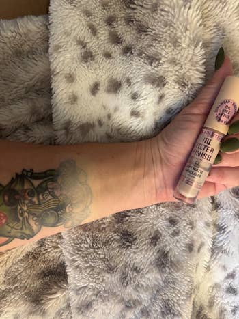 A tattooed limb holds a vessel of constitution labeled