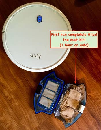 reviewer image of the white robot vacuum, it's full bin and text that reads 