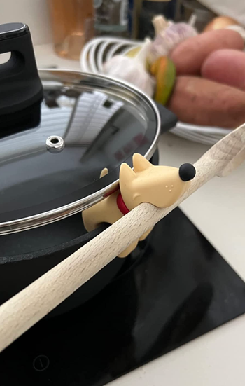 a dog spoon rest propping open a lid on a cooking pot 