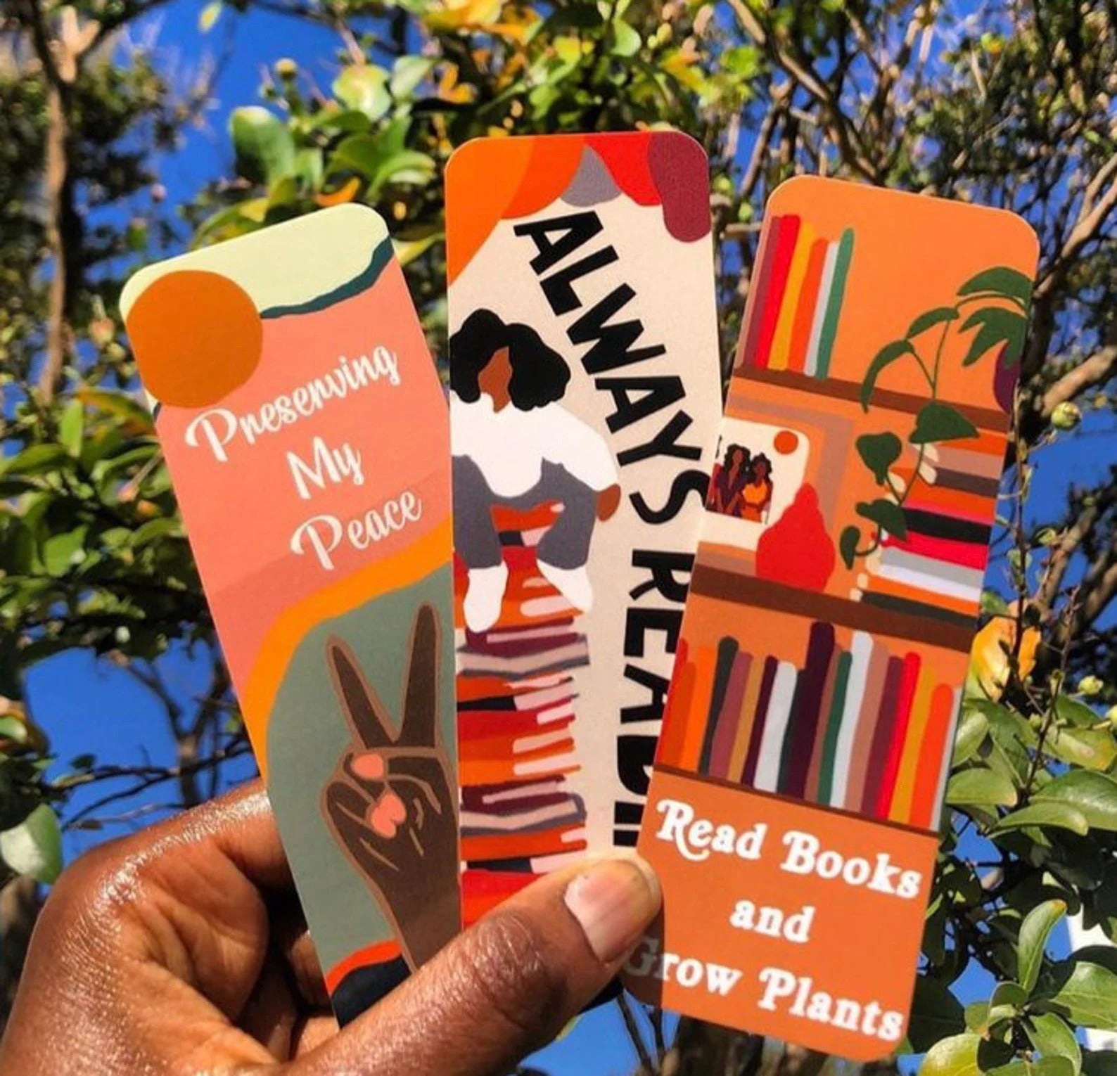 A hand holding three bookmarks