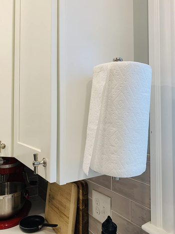 a reviewer photo of the paper towel holder mounted vertically on the side of a cabinet 