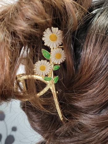 Hair accessory featuring a daisy plan  is styled successful  brunette hair, showcasing a floral-themed clip with intricate angiosperm  and leafage  details