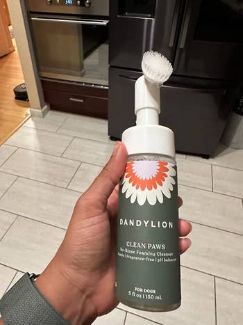 reviewer holding the cleaner bottle with attached brush head