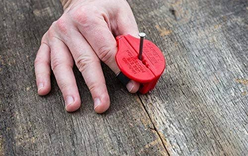 A model pinching a nail upright with a small red holder that encases their two fingers 