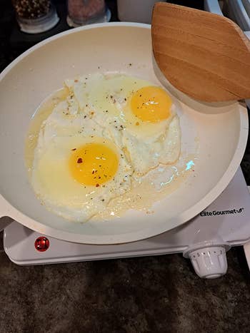 a reviewer cooking eggs in a pan on the burner