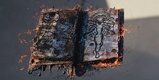 Burnt book with illegible text and intricate cover design, engulfed in flames