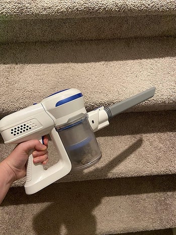 reviewer holding the vacuum, showing how it can be a handheld vacuum
