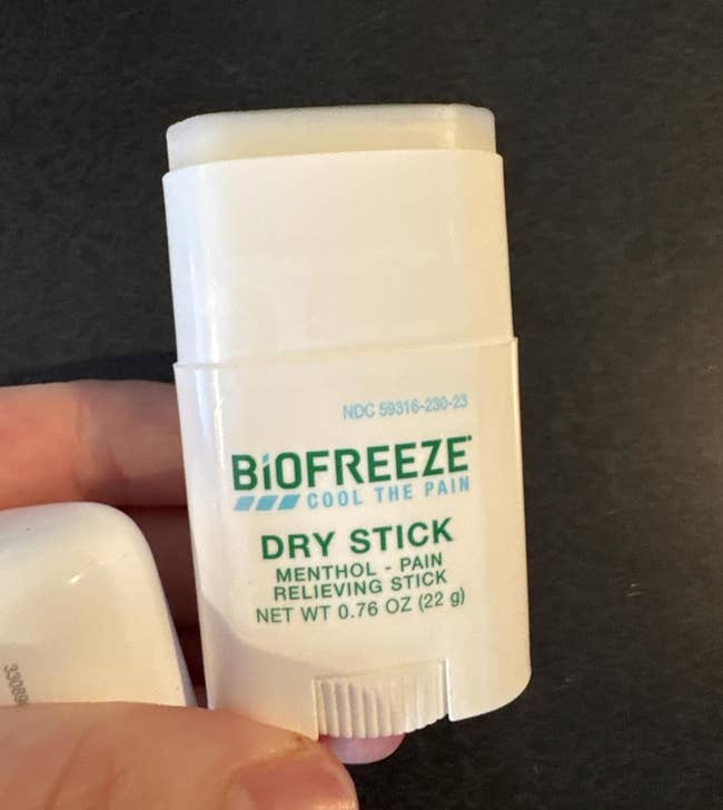 Hand holding a Biofreeze menthol pain-relieving adust  stick