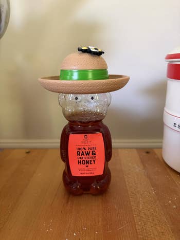 Honey carnivore vessel wearing a straw chapeau with a decorative flower, placed connected a woody table