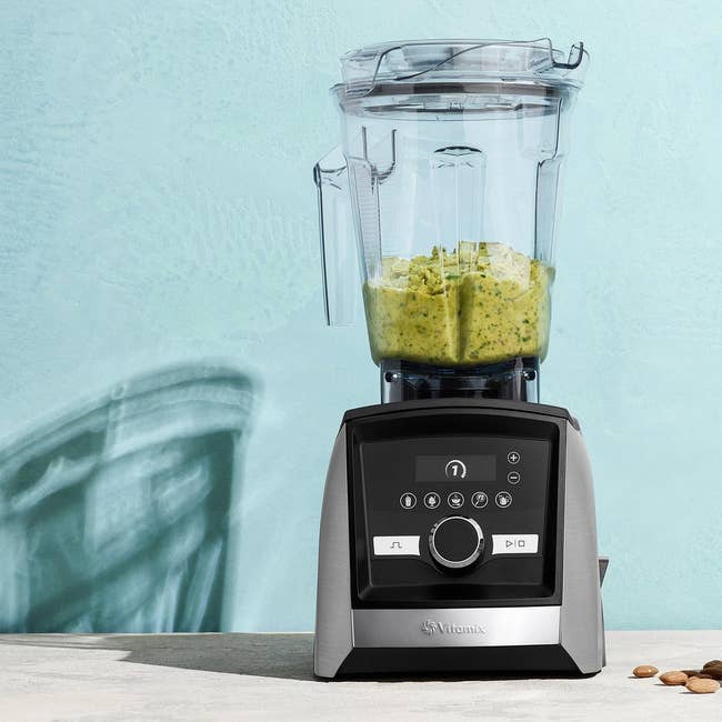 the black and stainless steel blender with blended greens in the container up top