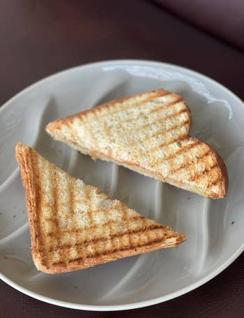 Toasted sandwich cut into triangles, placed on a white plate with grill marks visible. Suitable for a food-themed shopping article