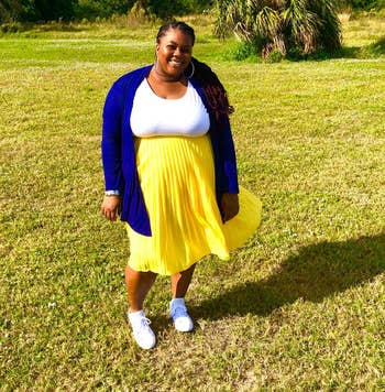reviewer wearing same style skirt in a yellow shade with a tee and blue cardigan
