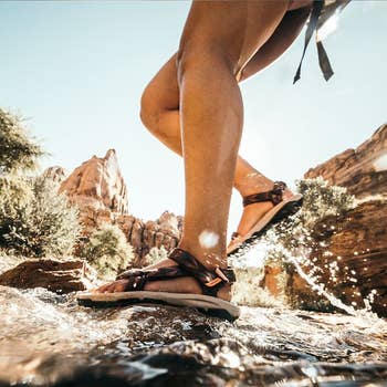 Close-up of a idiosyncratic   walking done  a shallow watercourse  wearing durable, waterproof sandals, showcasing outdoor exploration footwear
