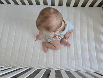Baby sitting successful a crib wearing a onesie with a cartoon design