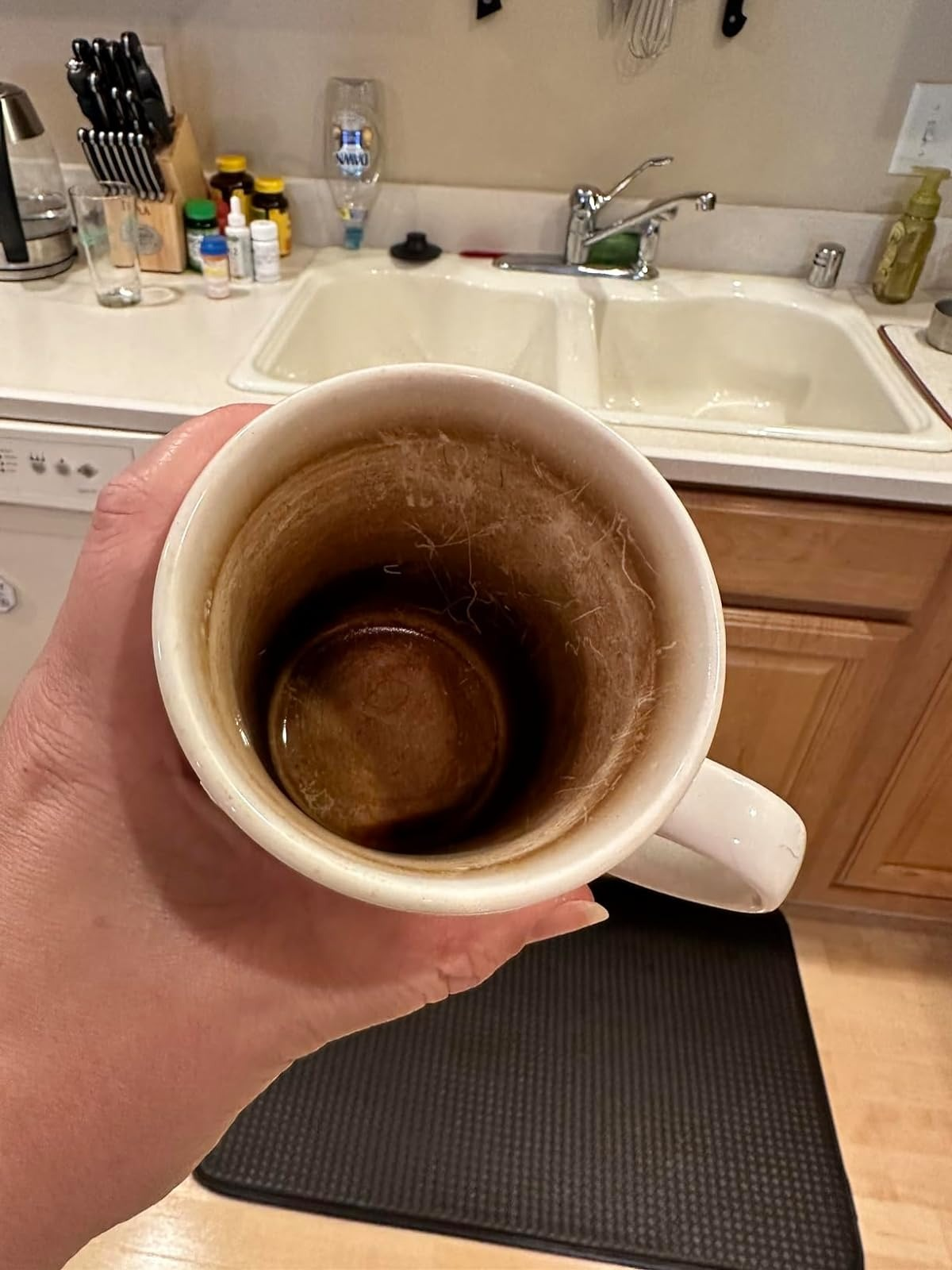 Hand holding a stained coffee mug in a kitchen