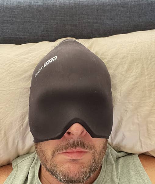 Reviewer laying down with the headache cap on covering down to their nose