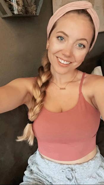 reviewer wearing a headband and tank top smiles for a selfie