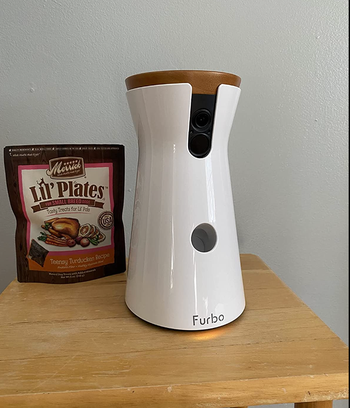 reviewer image of furbo camera on table next to bag of treats