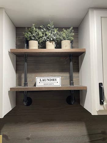 The three artificial plants on a shelf in a laundry room