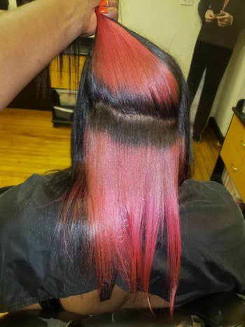 reviewer with straightened natural hair showing how vibrant the red is on their black hair