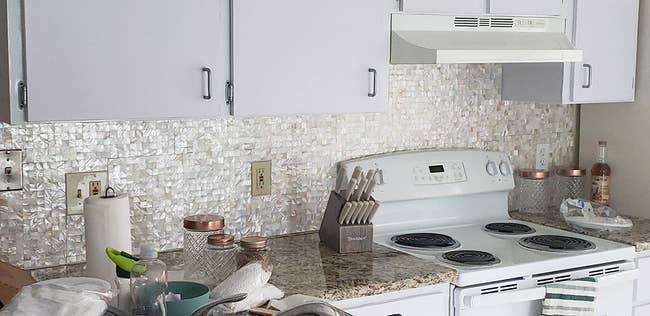 reviewer photo of the white mother of pearl wallpaper covering a kitchen backsplash