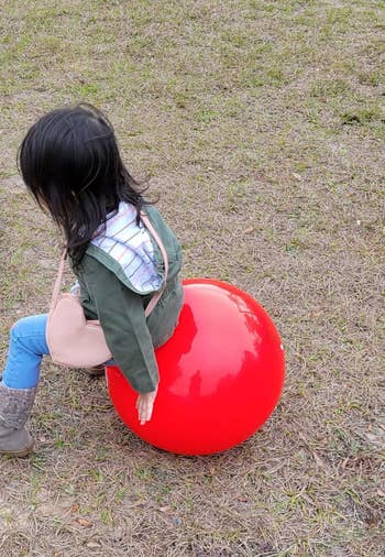reviewer image of a child sitting atop the red bouncing ball