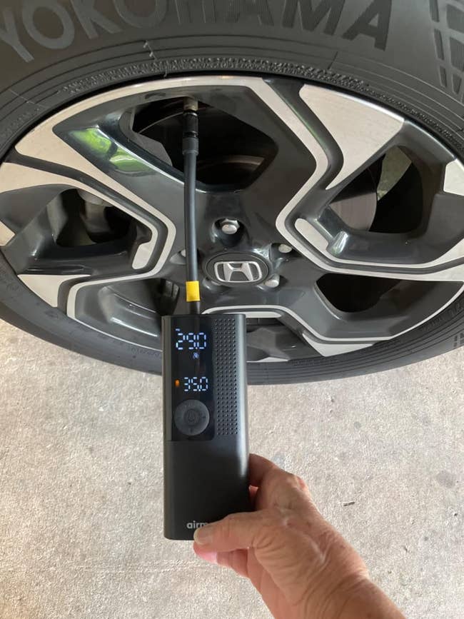 reviewer holding their tire inflator connected to their tire