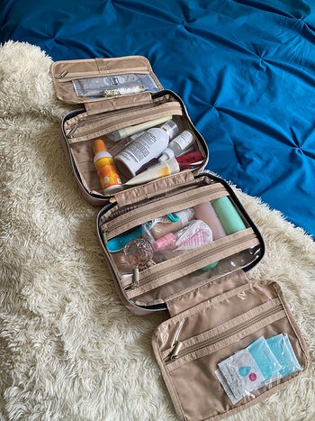 the pink toiletry bag opened showing all compartments filled with items