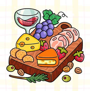 Charcuterie board with sliced meats, cheeses, grapes, strawberries, nuts, and a glass of wine