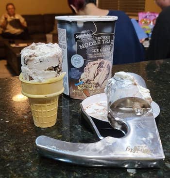 reviewer's ice cream scooper, with scooped ice cream in a cone next to container of ice cream