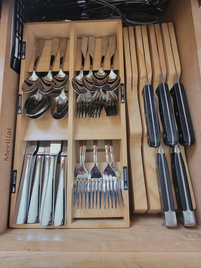 Organized kitchen drawer with various utensils, including spoons, forks, and knives, in separate compartments