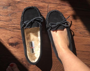 reviewer with one foot in the black moccasin and the other empty showing the soft fuzzy lining