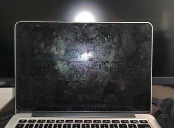 Dusty laptop screen with visible fingerprints and light glare, needing cleaning