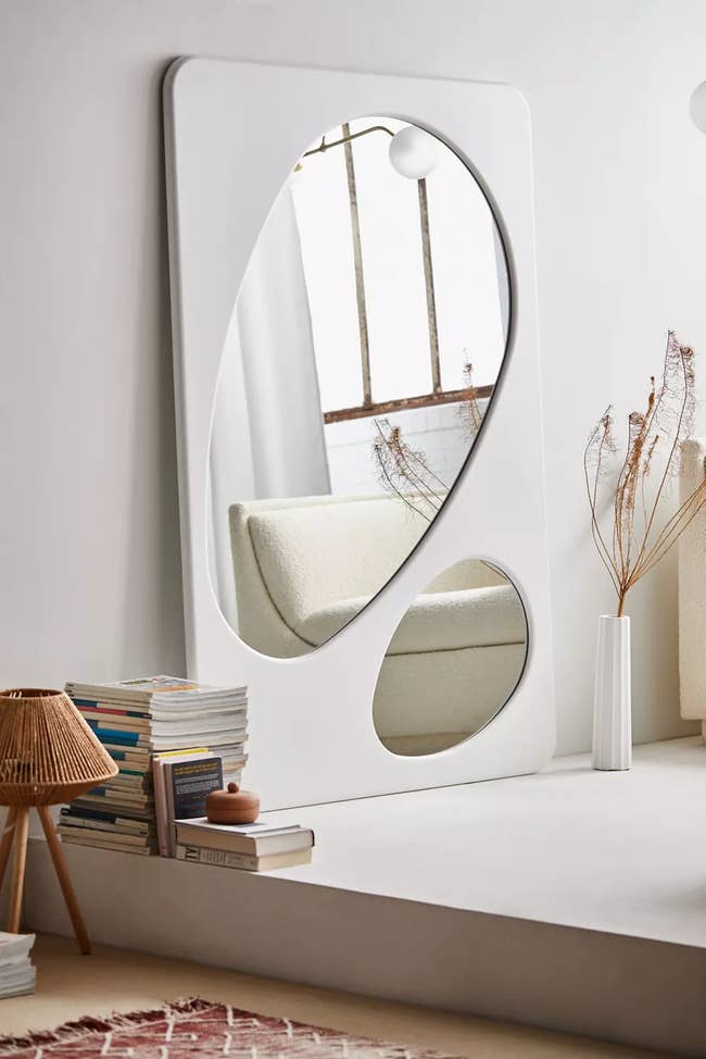 leaning wall mirror in rectangle shape with circular cut outs showing mirror behind white front