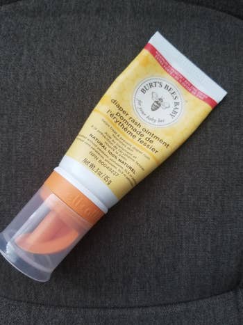 A reviewer's diaper rash cream bottle with the orange attachment