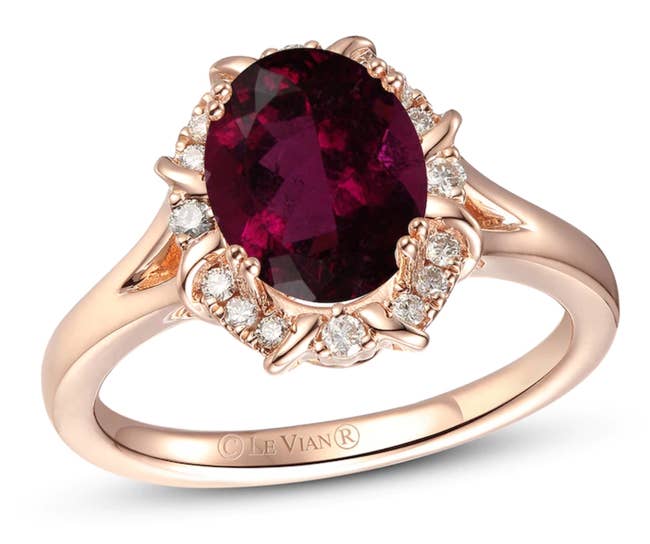 A sapphire colored stone surrounded by small diamonds and set on a rose gold band