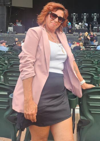 Person successful a pinkish blazer implicit a achromatic apical and achromatic mini skirt, posing astatine an lawsuit venue
